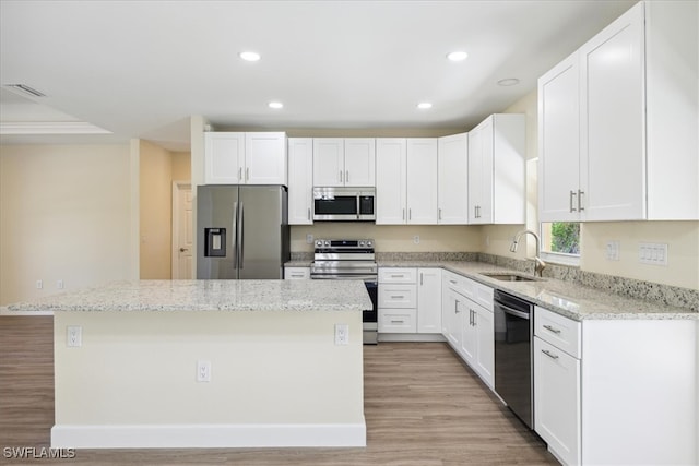 kitchen featuring sink, a kitchen island, white cabinets, and appliances with stainless steel finishes