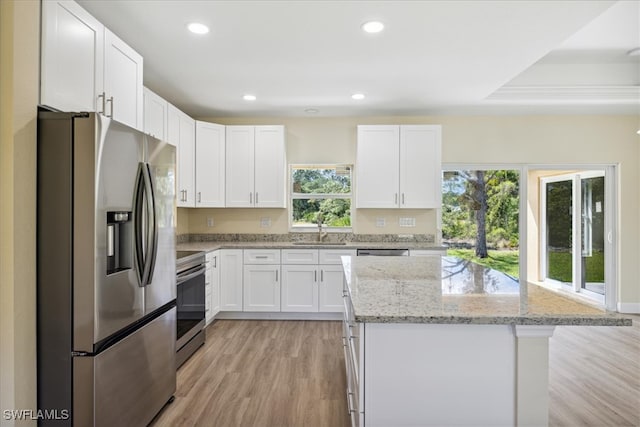 kitchen with white cabinets, a center island, stainless steel appliances, and light stone countertops