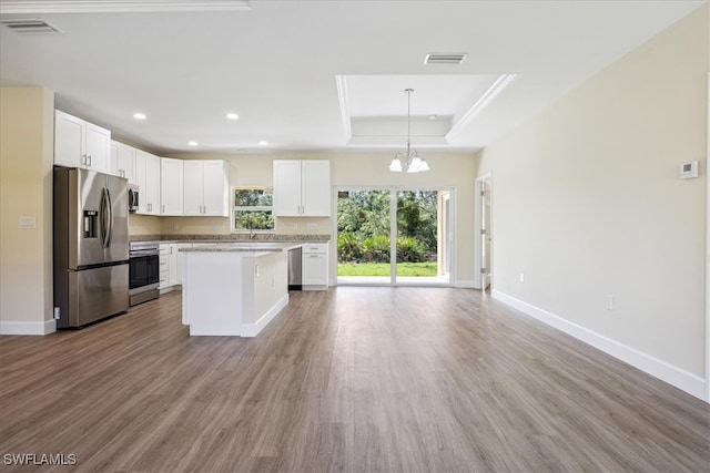 kitchen featuring pendant lighting, white cabinetry, appliances with stainless steel finishes, and a tray ceiling