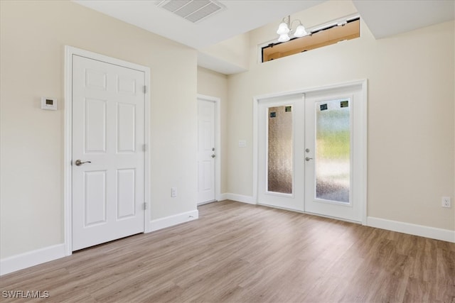 entrance foyer with a chandelier, french doors, and light hardwood / wood-style flooring