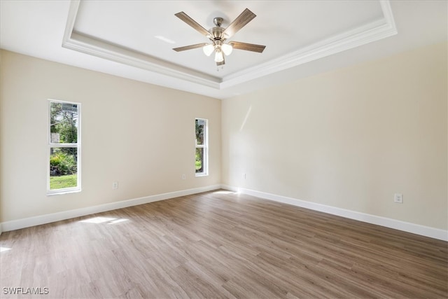 empty room featuring hardwood / wood-style flooring, ceiling fan, and a raised ceiling