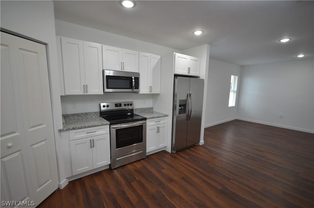 kitchen with white cabinetry, stainless steel appliances, light stone countertops, and dark wood-type flooring