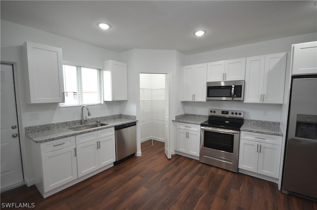 kitchen featuring sink, white cabinets, light stone counters, stainless steel appliances, and dark wood-type flooring