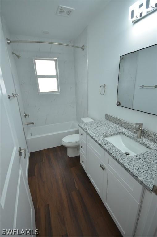 full bathroom featuring tiled shower / bath, wood-type flooring, toilet, and vanity