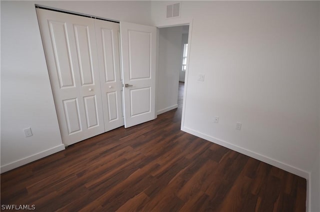 unfurnished bedroom featuring dark wood-type flooring and a closet