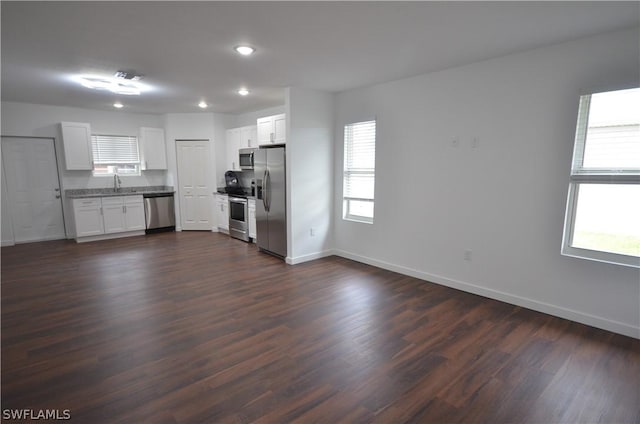 unfurnished living room with plenty of natural light, dark wood-type flooring, and sink