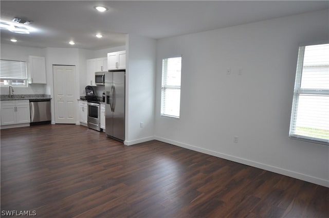 kitchen featuring white cabinetry, a healthy amount of sunlight, appliances with stainless steel finishes, and dark hardwood / wood-style floors