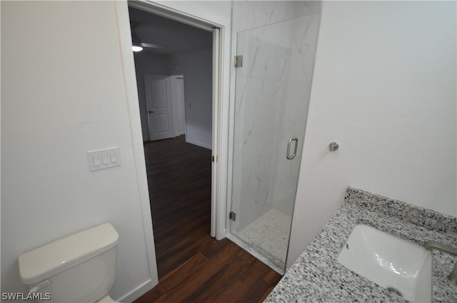 bathroom featuring hardwood / wood-style flooring, vanity, a shower with shower door, and toilet