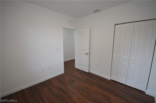 unfurnished bedroom featuring dark hardwood / wood-style floors and a closet