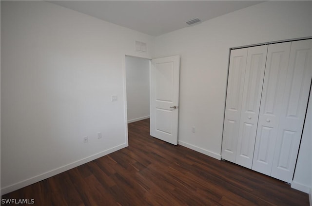 unfurnished bedroom with dark hardwood / wood-style flooring and a closet