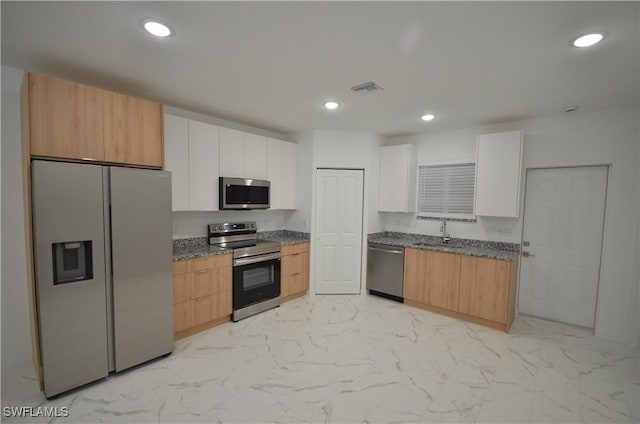 kitchen featuring stainless steel appliances, white cabinetry, sink, and dark stone countertops