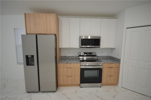 kitchen with white cabinetry, appliances with stainless steel finishes, and dark stone counters