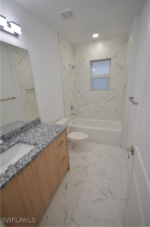 full bathroom with tiled shower / bath, vanity, and toilet