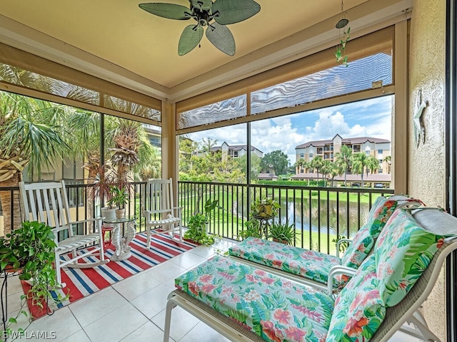 sunroom featuring ceiling fan and a water view