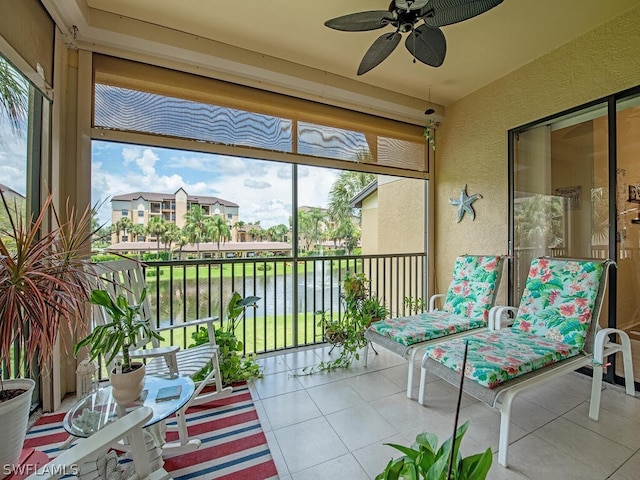 sunroom with ceiling fan and a water view