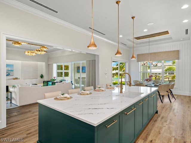 kitchen featuring decorative light fixtures, sink, an island with sink, and an inviting chandelier