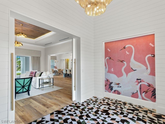 entrance foyer with hardwood / wood-style floors, crown molding, and an inviting chandelier