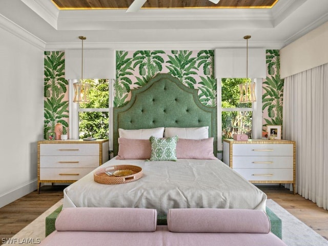 bedroom featuring a raised ceiling, wood-type flooring, and crown molding