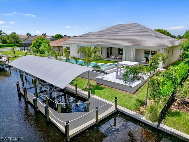 back of house with a patio, a lawn, a water view, and boat lift