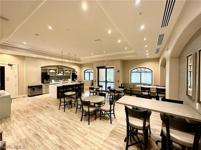 dining room with a raised ceiling, light wood-type flooring, and ornamental molding