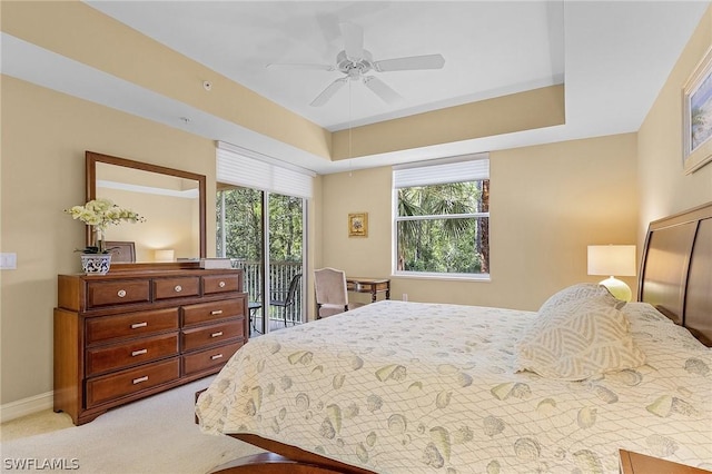 carpeted bedroom featuring ceiling fan, a tray ceiling, and access to outside