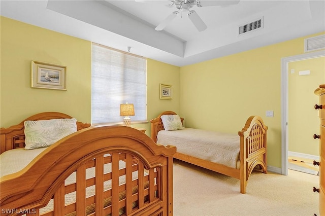 bedroom featuring ceiling fan, a raised ceiling, and light colored carpet