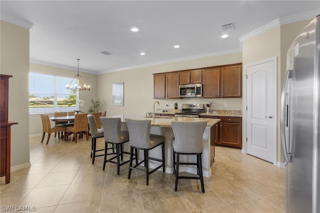 kitchen with light stone countertops, stainless steel appliances, decorative light fixtures, a chandelier, and an island with sink