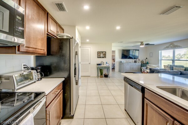 kitchen with decorative backsplash, stainless steel appliances, light tile patterned floors, and ceiling fan