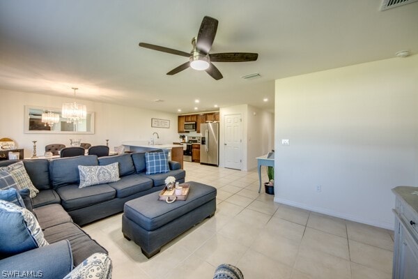 tiled living room featuring sink and ceiling fan with notable chandelier