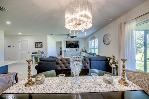 tiled dining space featuring ceiling fan with notable chandelier and a healthy amount of sunlight