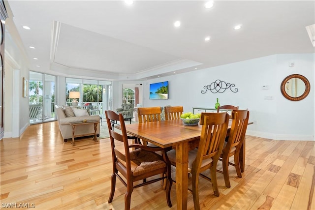 dining space with light wood-type flooring and a raised ceiling