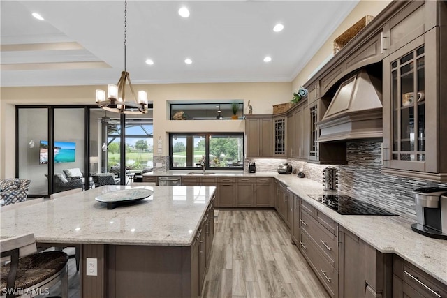 kitchen with pendant lighting, a kitchen breakfast bar, decorative backsplash, custom exhaust hood, and light stone countertops