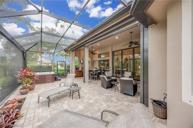 view of patio / terrace featuring a hot tub, ceiling fan, and glass enclosure