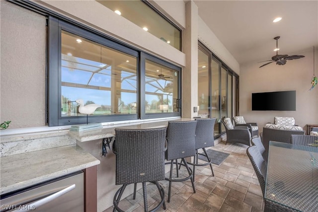 view of patio with a bar, ceiling fan, and an outdoor living space