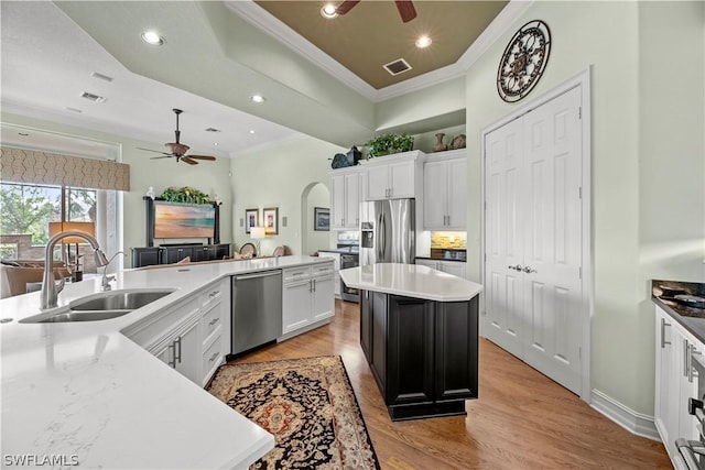 kitchen with arched walkways, visible vents, appliances with stainless steel finishes, a sink, and a kitchen island