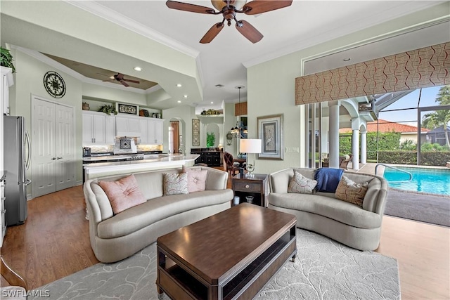 living area with ceiling fan, ornamental molding, wood finished floors, and recessed lighting