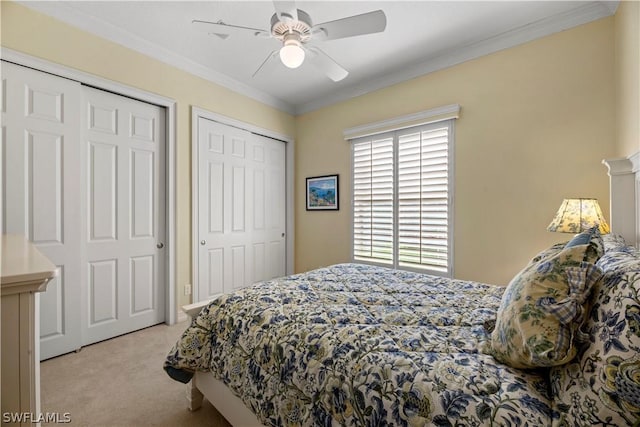 bedroom with ornamental molding, two closets, a ceiling fan, and light colored carpet