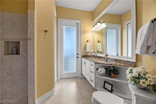 full bathroom featuring tile patterned flooring, tiled shower, vanity, and toilet