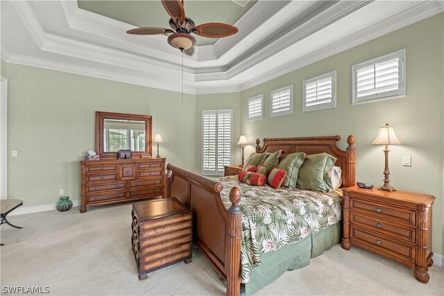 bedroom with carpet floors, a ceiling fan, baseboards, ornamental molding, and a tray ceiling