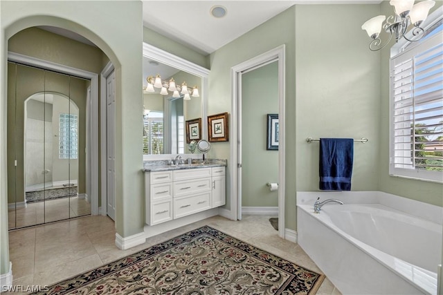 bathroom featuring a garden tub, a notable chandelier, vanity, and tile patterned floors