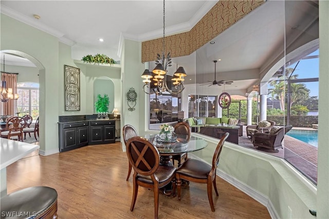 dining space with a chandelier, ornamental molding, and wood finished floors