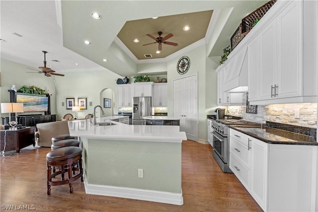 kitchen with crown molding, a spacious island, appliances with stainless steel finishes, a sink, and wood finished floors