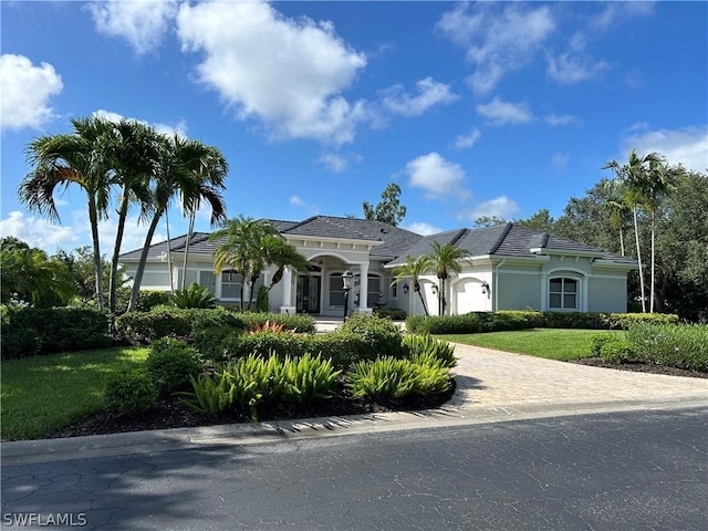 mediterranean / spanish house with a front yard, an attached garage, and stucco siding