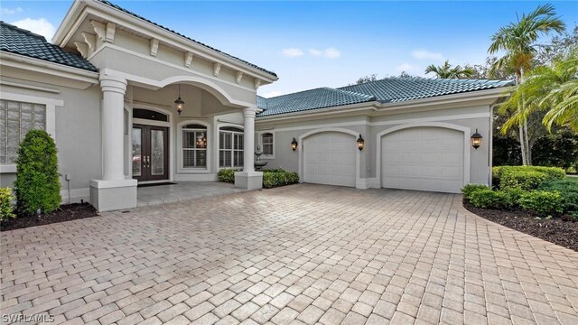 view of front of home featuring french doors, decorative driveway, an attached garage, and a tile roof