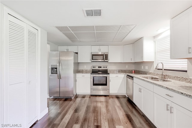 kitchen with white cabinetry, hardwood / wood-style flooring, stainless steel appliances, sink, and light stone counters