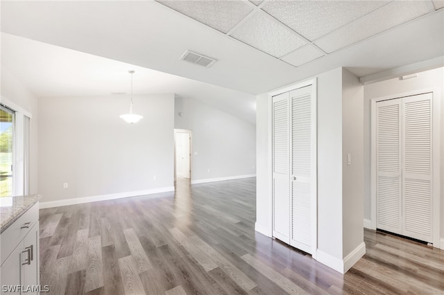 interior space with lofted ceiling, a drop ceiling, and hardwood / wood-style floors