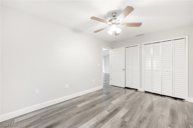 unfurnished bedroom featuring two closets, light hardwood / wood-style flooring, and ceiling fan