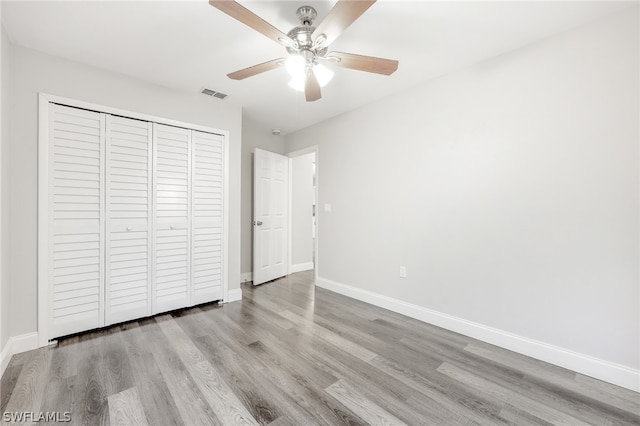 unfurnished bedroom with ceiling fan, hardwood / wood-style floors, and a closet