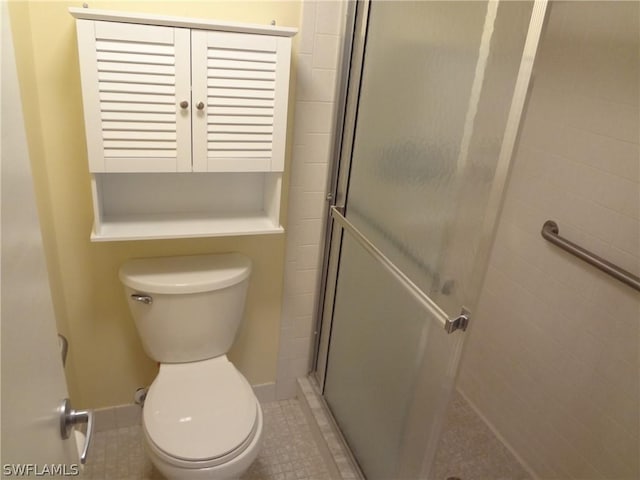 bathroom with toilet, a shower with door, and tile patterned flooring