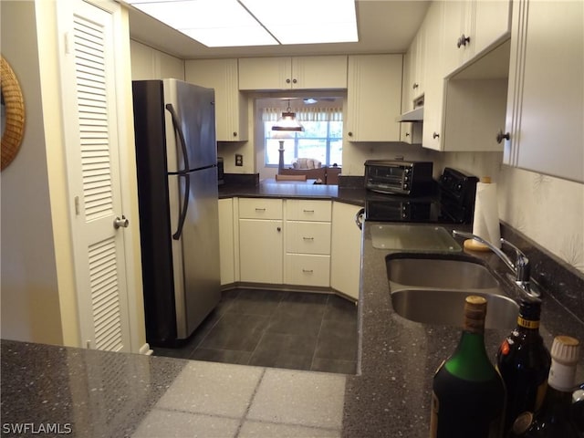 kitchen with sink, stainless steel fridge, cream cabinets, and electric range oven